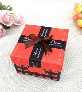 Dettaglio della scatola regalo di Natale rossa con cuori e fiocco elegante in nastro