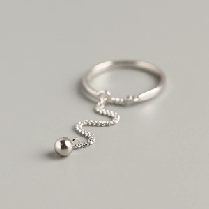 Minimalist S925 sterling silver chain ring with a dangling polished bead on grey background