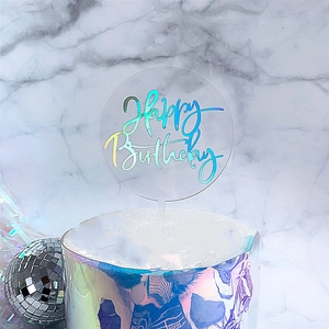 Close-up of transparent acrylic Happy Birthday cake topper with laser holographic effect