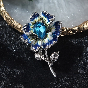 Macro view of flower brooch with blue gradient enamel and teardrop crystal centerpiece