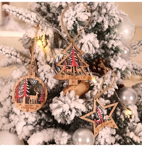 Close-up of wooden Christmas tree and reindeer ornaments hanging on a snowy branch