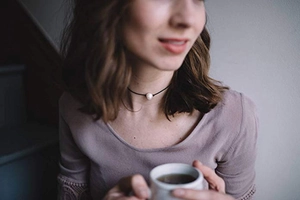 Detail of a minimalist black leather cord choker with a single white freshwater pearl