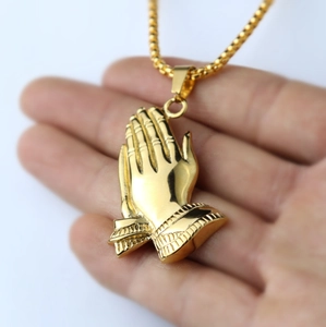 Detailed view of a gold-plated praying hands pendant on a stainless steel chain