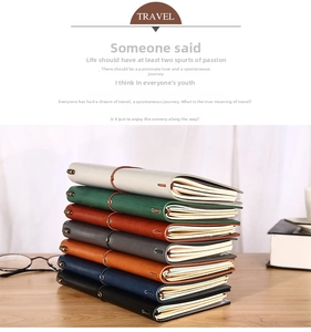 Close-up of stacked leather traveler notebooks in seven colors on a wooden table