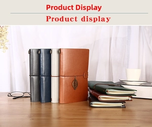 Detail of colorful leather journals with elastic closure and vintage metal leaf pendants