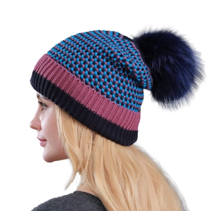 Winter knitted beanie with colorful checkered pattern and large fluffy faux fur pompom