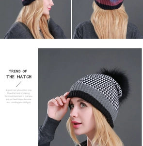 Close-up of the black and white plaid knit beanie with a fluffy raccoon fur pom-pom detail