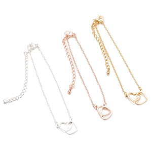Double heart pendant bracelet in gold, silver, and rose gold finishes on white background