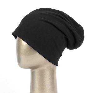 Detailed view of a black slouchy knit beanie on a model head with a clean white background