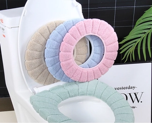 Detail of four colorful plush toilet seat covers with striped texture on a toilet