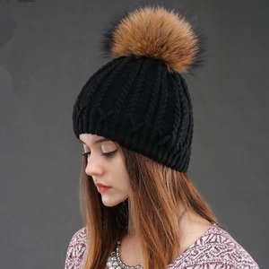 Black knit beanie with a fluffy fur pom pom and classic cable stitch texture for winter