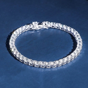 Detailed view of a silver tennis bracelet with sparkling round clear zircons on blue background