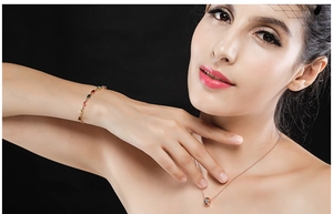 Dettaglio di bracciale e collana in oro con pietre colorate su una modella