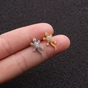 Close-up of gecko stud earrings in silver and gold with clear zircon on fingertips