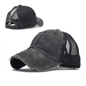 Close-up of distressed cotton texture and mesh design on a black ponytail baseball cap