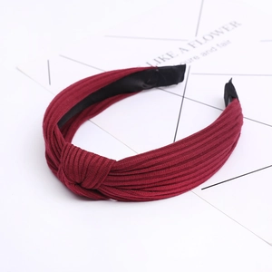 Close-up of wine red knitted headband featuring a cross knot and vertical striped texture