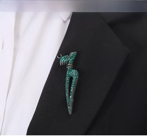 Close-up of a sparkling green crystal animal brooch pinned to a black suit lapel