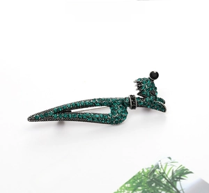 Detail of high heel brooch featuring emerald green crystals and black accents