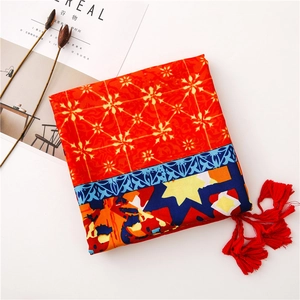 Detailed view of red ethnic style shawl with floral patterns and vibrant tassels