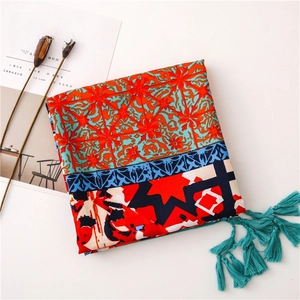 Detail of colorful ethnic print shawl with blue tassels and geometric floral pattern