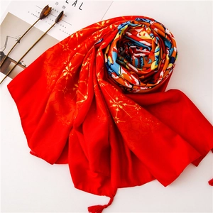 Macro detail of red ethnic scarf with gold star patterns and fringe tassels