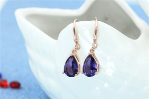 Detailed view of teardrop purple amethyst earrings hanging on a ceramic swan display