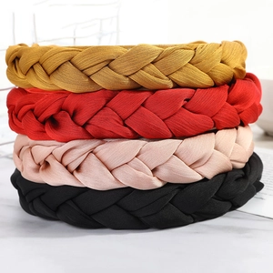 Braided fabric headbands in red, yellow, pink, and black colors on marble surface