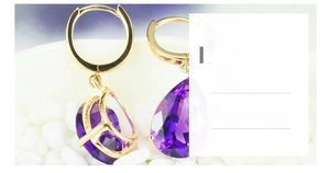 Macro shot of pear-cut amethyst earrings with gold plating on white pebble background