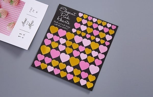 Detail of pink and gold heart-shaped scrapbooking stickers on a black background