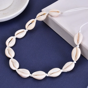 Detailed close-up of natural white cowrie shells on handmade bohemian woven necklace