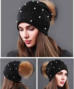 Detailed view of women's black knitted pearl hat with premium brown fur pom-pom