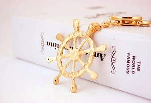 Detail shot of golden ship wheel keychain with crystal accents and polished metal link