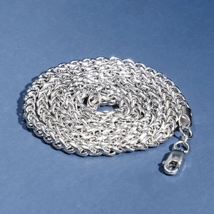 Macro shot of silver woven chain necklace with lobster clasp on dark blue background