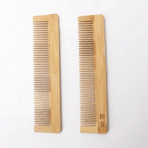 Detailed texture of dual natural bamboo fine-tooth combs on a minimalist white background