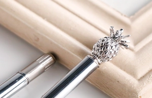 Macro shot of silver metal pen featuring a detailed pineapple-shaped top ornament