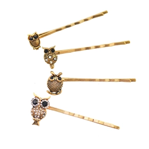 Detail view of four vintage golden alloy hairpins with rhinestone owl designs on white background