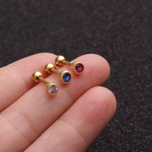 Three gold stainless steel stud earrings with clear blue and red zircons on finger