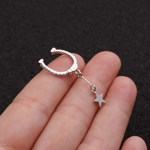 Detailed macro view of silver star drop ear clip with micro-pave zircons on a finger