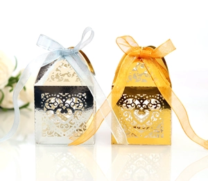 Detail of laser-cut heart pattern on gold and silver candy boxes with ribbons