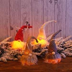 Macro shot of illuminated Christmas Gnomes with warm LED lights on a wooden desk
