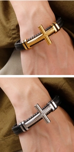 Close-up of men's braided leather bracelet with gold and silver cross metal charms