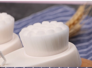 Close-up of soft white bristles on manual facial cleansing brush with beige handle