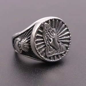Macro shot of silver praying hands relief on vintage stainless steel ring band