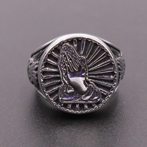 Detail of vintage silver praying hand ring featuring intricate gothic relief patterns