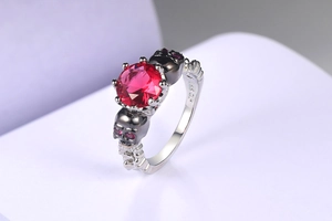 Macro shot of gothic skull ring with red zircon and 18K GP engraving on silver band