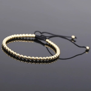 Close-up of adjustable black braided cord bracelet with gold hematite beads and polished finish