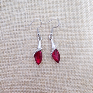 Detailed close-up of red teardrop crystal earrings with rhinestones on a beige background