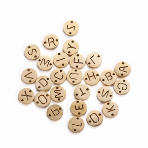 Macro view of gold stainless steel round letter charms with double holes for DIY jewelry