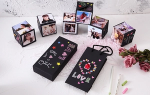 DIY surprise bounce box set with black photo cubes and gift bag on decorative background
