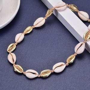 Bohemian gold shell necklace with white pearls and woven rope on blue background